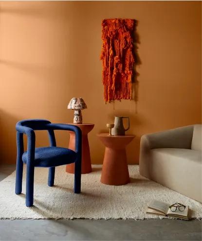 Ambiente com parede na cor Calcita Alaranjada Suvinil - Na frente, sofá, cadeira e objetos de barro sobre a mesa